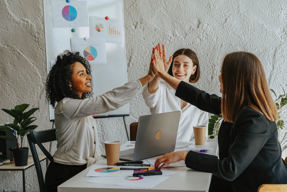 Drie vrouwen geven high five tijdens het voeren van een voortgangsgesprek